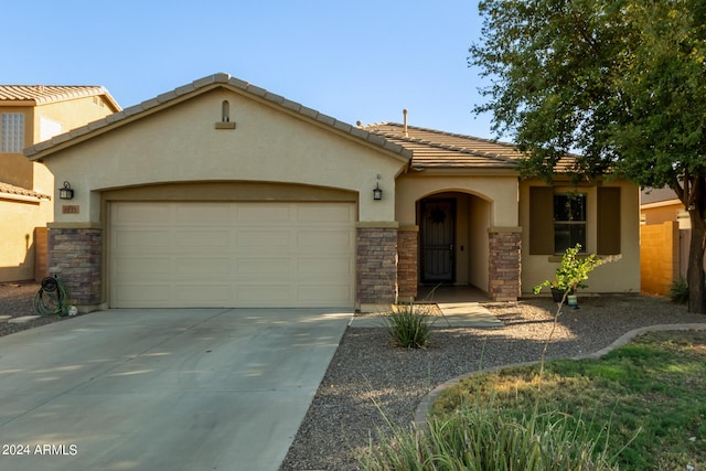 view of front of home with stone siding, a garage, stucco siding, and concrete driveway