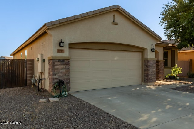 view of front of home with stone siding, stucco siding, a garage, and driveway
