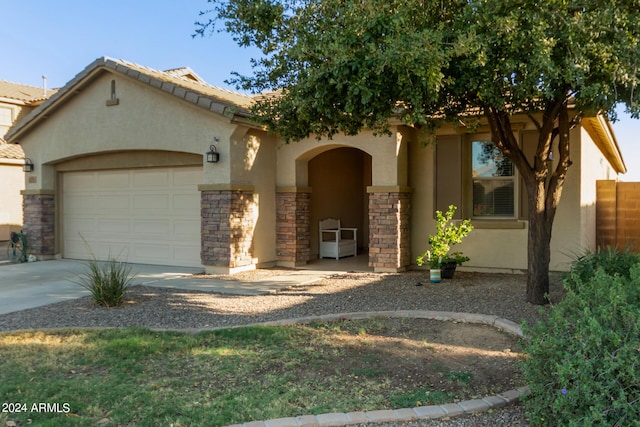view of front of house with stucco siding, a garage, driveway, and stone siding