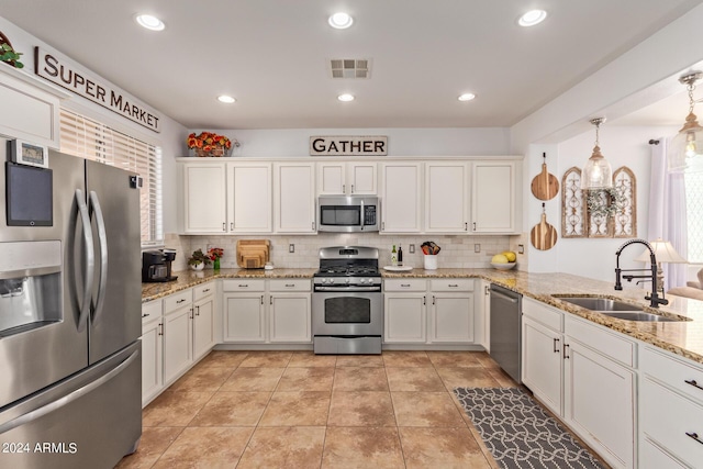 kitchen with stainless steel appliances, a sink, tasteful backsplash, white cabinets, and recessed lighting