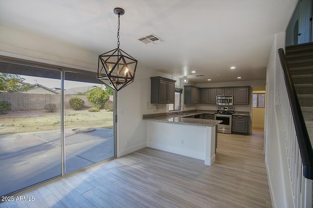 kitchen featuring visible vents, a chandelier, a peninsula, stainless steel appliances, and a sink