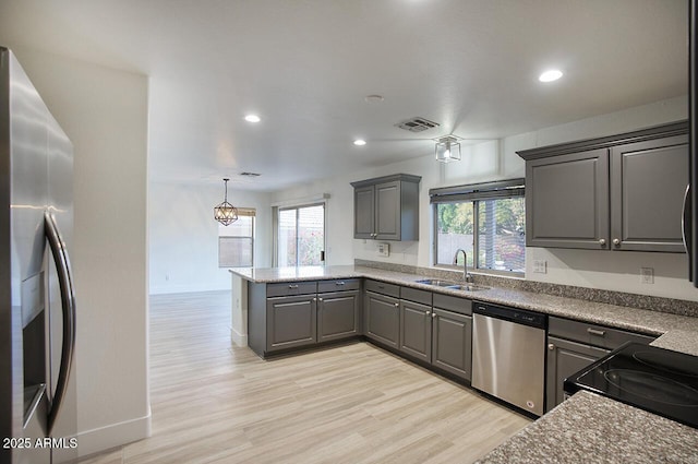 kitchen featuring visible vents, gray cabinets, a sink, appliances with stainless steel finishes, and a peninsula