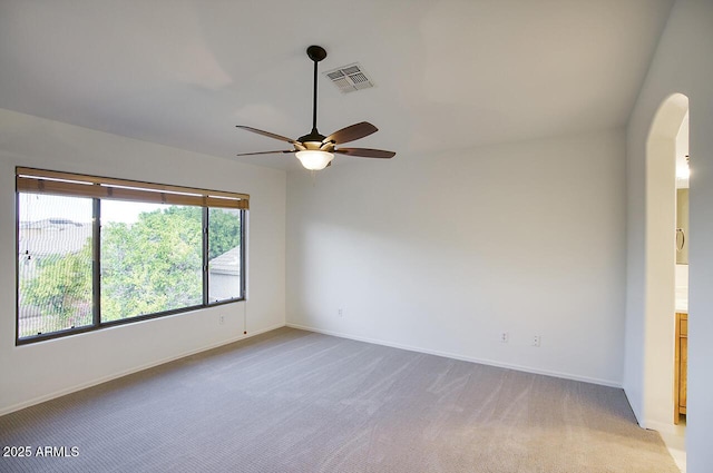 unfurnished room with visible vents, arched walkways, baseboards, light colored carpet, and ceiling fan