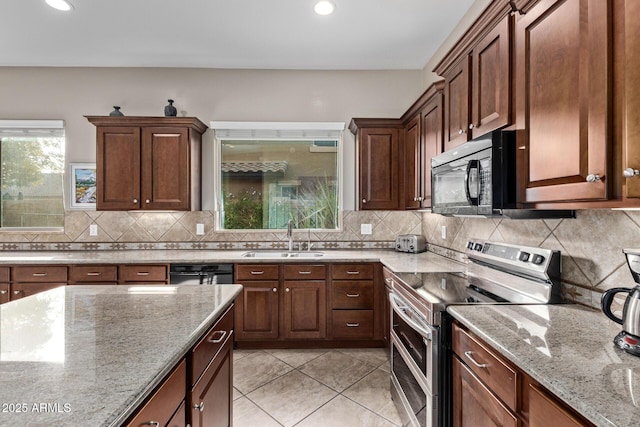 kitchen featuring double oven range, sink, light stone counters, and decorative backsplash