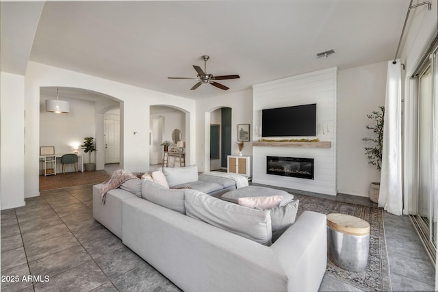 living room featuring ceiling fan and a fireplace