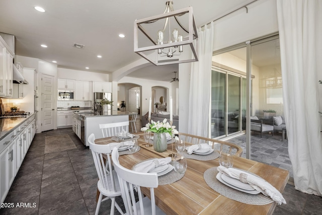 dining space with ceiling fan with notable chandelier