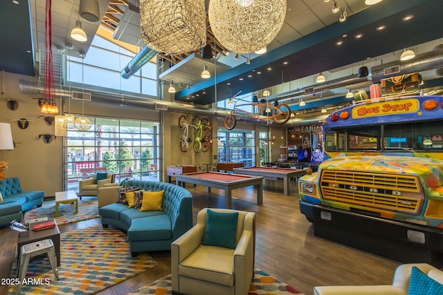 game room with a high ceiling, wood-type flooring, pool table, and a chandelier