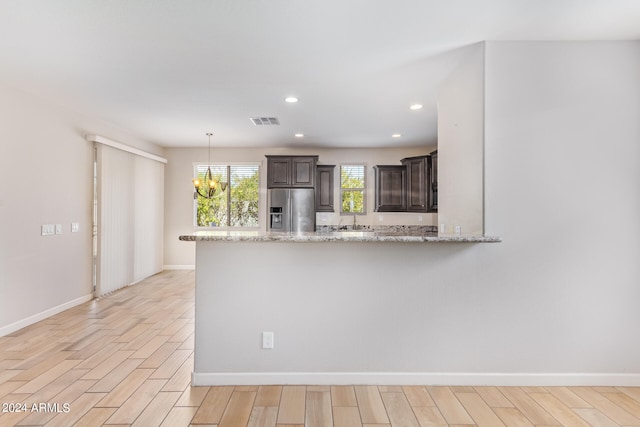 kitchen with a chandelier, stainless steel fridge, kitchen peninsula, and light hardwood / wood-style floors