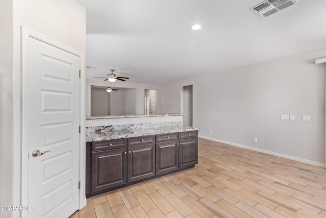 kitchen featuring light stone countertops, dark brown cabinets, light wood-type flooring, and ceiling fan