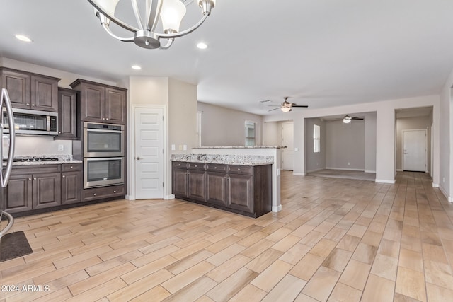 kitchen featuring appliances with stainless steel finishes, dark brown cabinetry, ceiling fan with notable chandelier, and light wood-type flooring