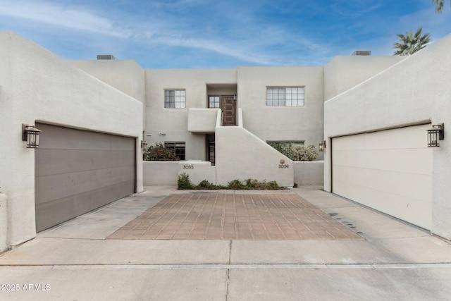 view of front of house with a garage, driveway, and stucco siding