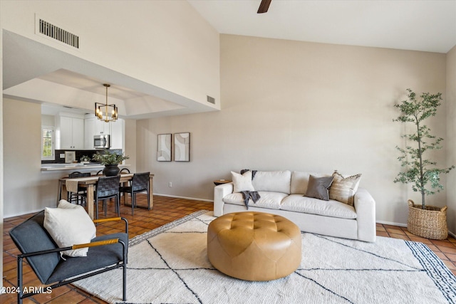 tiled living area with a raised ceiling, visible vents, baseboards, and ceiling fan with notable chandelier