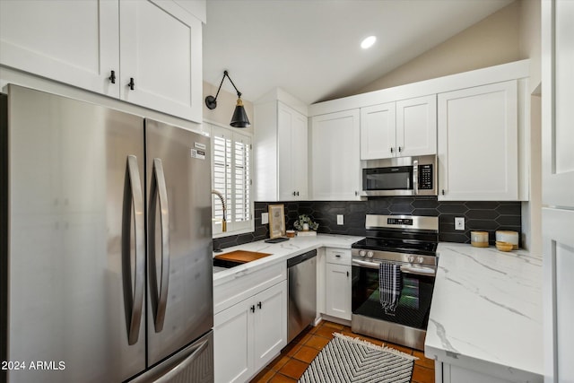 kitchen featuring vaulted ceiling, appliances with stainless steel finishes, white cabinetry, and tasteful backsplash