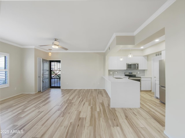 kitchen featuring light countertops, appliances with stainless steel finishes, open floor plan, white cabinets, and a sink