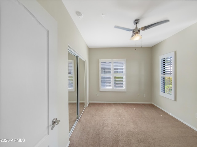 unfurnished bedroom featuring light carpet, a closet, a ceiling fan, and baseboards