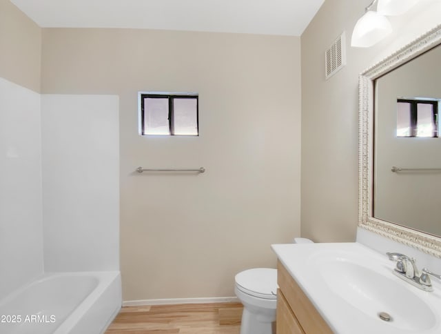 bathroom with visible vents, toilet, vanity, wood finished floors, and baseboards