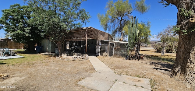 rear view of property featuring an outdoor structure and fence