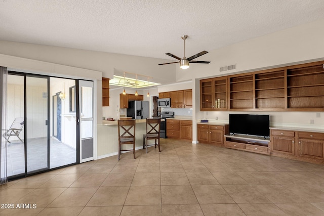 kitchen with a ceiling fan, brown cabinetry, visible vents, open shelves, and stainless steel appliances