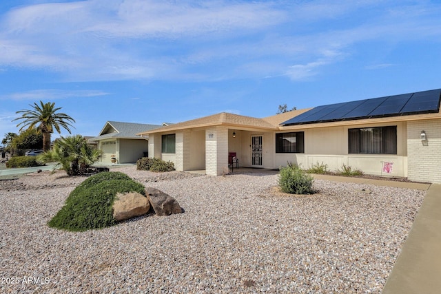 ranch-style home featuring brick siding and roof mounted solar panels