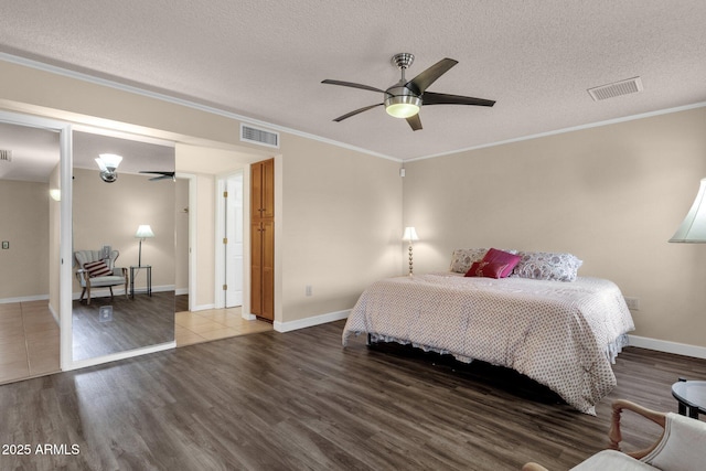 bedroom featuring visible vents, a textured ceiling, wood finished floors, and ornamental molding