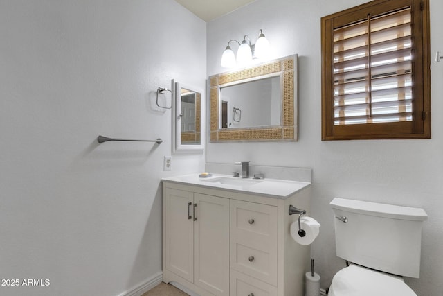 bathroom with toilet, vanity, and baseboards