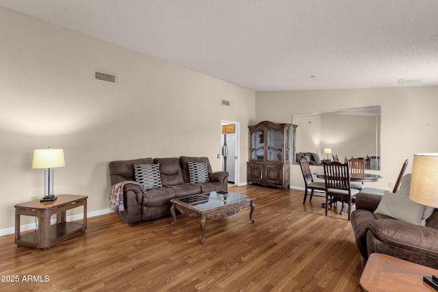 living area with visible vents, wood finished floors, and vaulted ceiling