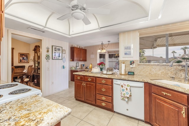 kitchen with light stone counters, ceiling fan with notable chandelier, sink, light tile patterned floors, and dishwasher