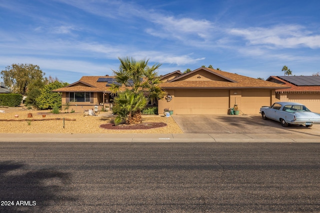 ranch-style home with a garage and solar panels