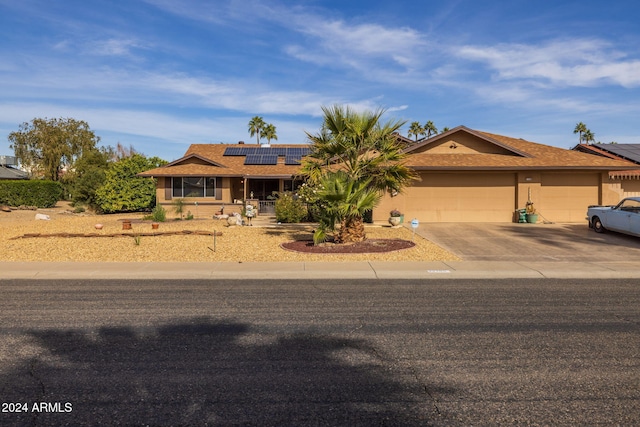 single story home featuring solar panels and a garage