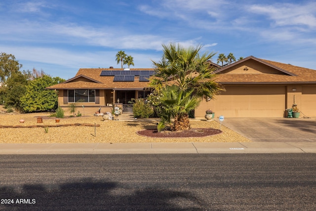 ranch-style home featuring solar panels, a garage, and a porch