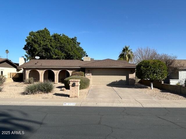 ranch-style home with concrete driveway, a garage, and a chimney