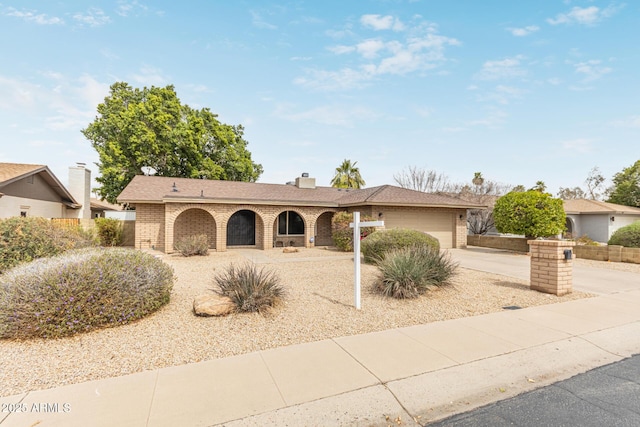 ranch-style house featuring brick siding, a chimney, concrete driveway, and an attached garage