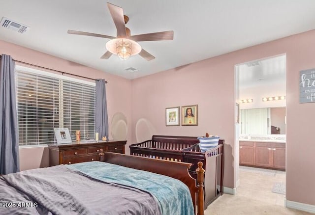 bedroom featuring light carpet, ceiling fan, and ensuite bath