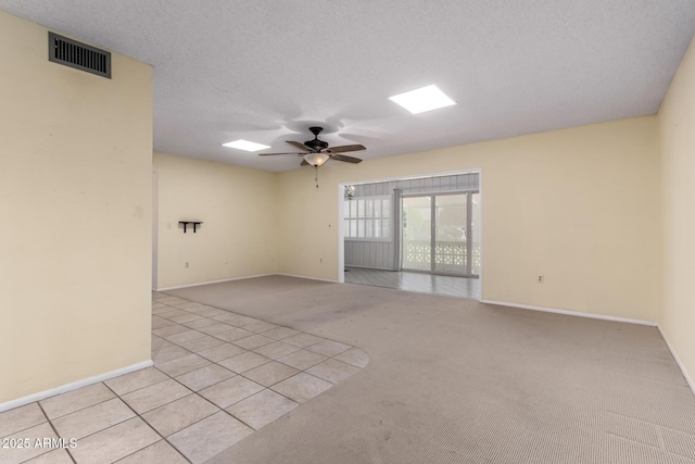 spare room with visible vents, light carpet, a textured ceiling, baseboards, and ceiling fan