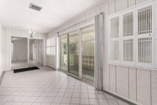 interior space featuring tile patterned flooring, a notable chandelier, visible vents, and a textured ceiling