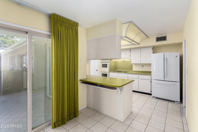 kitchen with white cabinetry, white appliances, light tile patterned flooring, and a peninsula