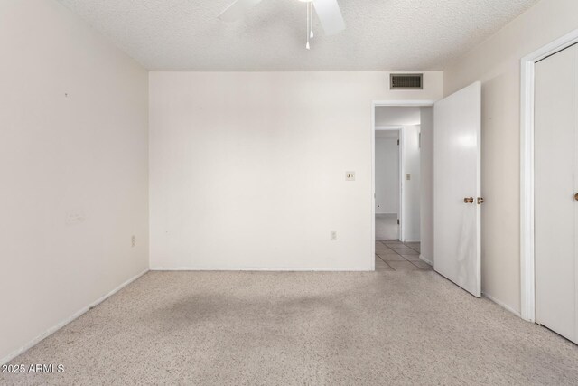 empty room with a textured ceiling, a ceiling fan, visible vents, and light carpet