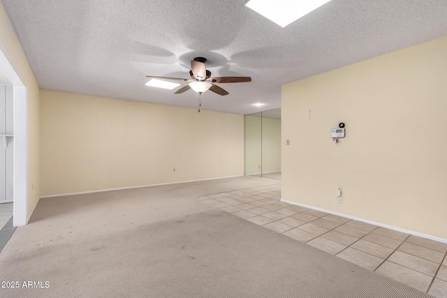 spare room with light tile patterned floors, baseboards, ceiling fan, a textured ceiling, and light colored carpet