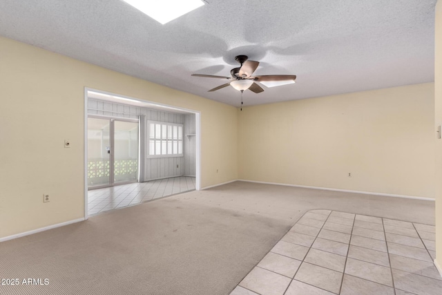 unfurnished room with baseboards, light colored carpet, ceiling fan, and a textured ceiling