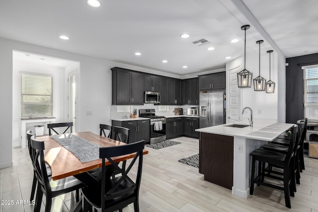4352 N 91st Gln, Phoenix, AZ 85037 - kitchen with appliances with stainless steel finishes, a sink, light countertops, a kitchen breakfast bar, and recessed lighting