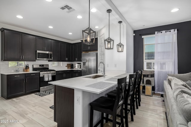 4352 N 91st Gln, Phoenix, AZ 85037 - kitchen with stainless steel appliances, a sink, a kitchen bar, light countertops, and decorative backsplash