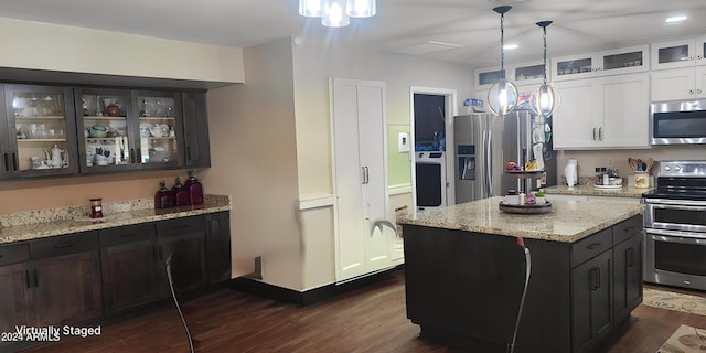 kitchen featuring dark wood finished floors, stainless steel appliances, hanging light fixtures, white cabinetry, and a center island