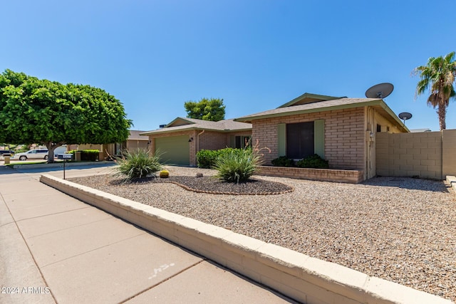 single story home featuring brick siding, an attached garage, driveway, and fence