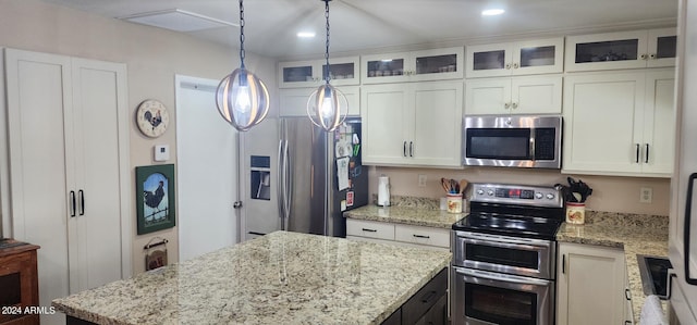 kitchen featuring light stone counters, stainless steel appliances, white cabinets, glass insert cabinets, and a center island