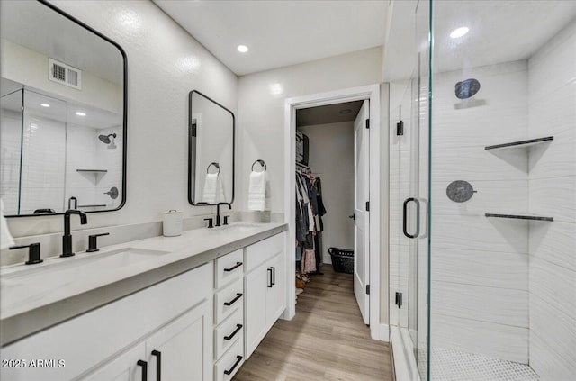 bathroom with hardwood / wood-style flooring, walk in shower, and vanity