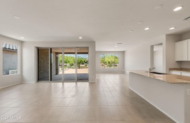 unfurnished living room featuring light tile patterned floors and sink