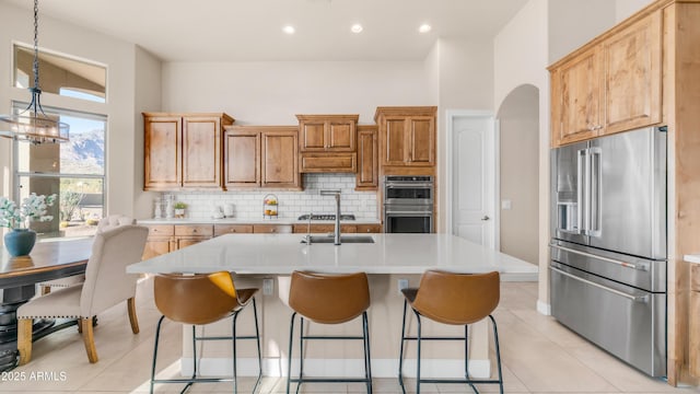 9864 E Baseline Ave, Gold Canyon, AZ 85118 - kitchen with stainless steel appliances, light countertops, backsplash, arched walkways, and a center island with sink