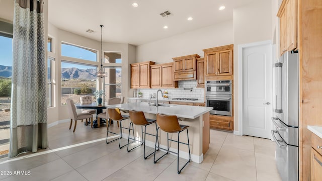 9864 E Baseline Ave, Gold Canyon, AZ 85118 - kitchen with appliances with stainless steel finishes, tasteful backsplash, light countertops, a center island with sink, and a breakfast bar