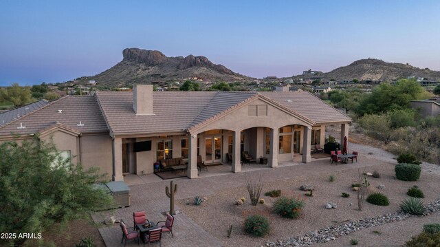 9864 E Baseline Ave, Gold Canyon, AZ 85118 - back of house at dusk with a chimney, a patio, a mountain view, a tile roof, and stucco siding