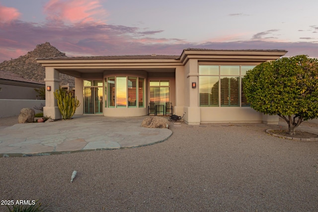 back house at dusk featuring a patio area